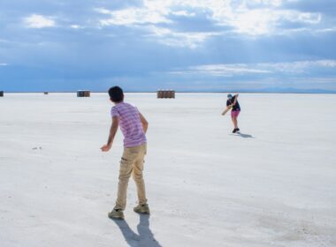 A couple of people that are standing in the sand
