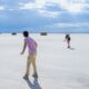 A couple of people that are standing in the sand