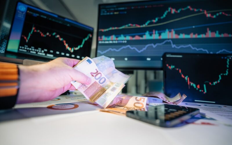 A person holding money in front of a computer screen
