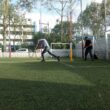 Two men playing cricket on a turf field.