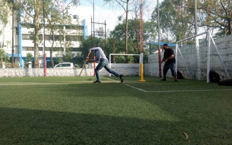 Two men playing cricket on a turf field.