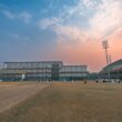 Cricket stadium with floodlights at sunset