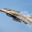 a fighter jet flying through a blue sky