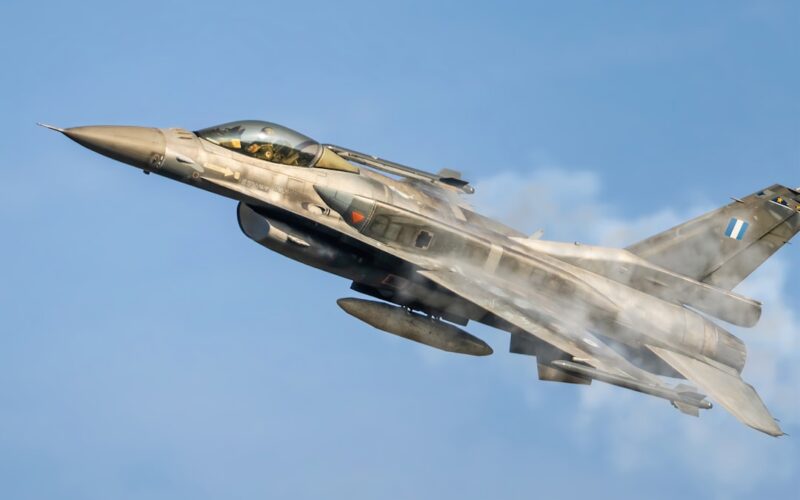 a fighter jet flying through a blue sky