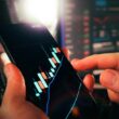 Hands holding smartphone showing stock market data