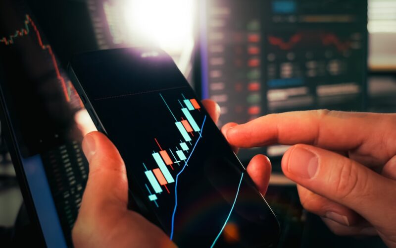 Hands holding smartphone showing stock market data
