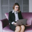 a woman sitting on a couch using a laptop computer