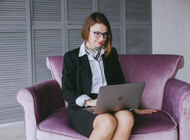 a woman sitting on a couch using a laptop computer