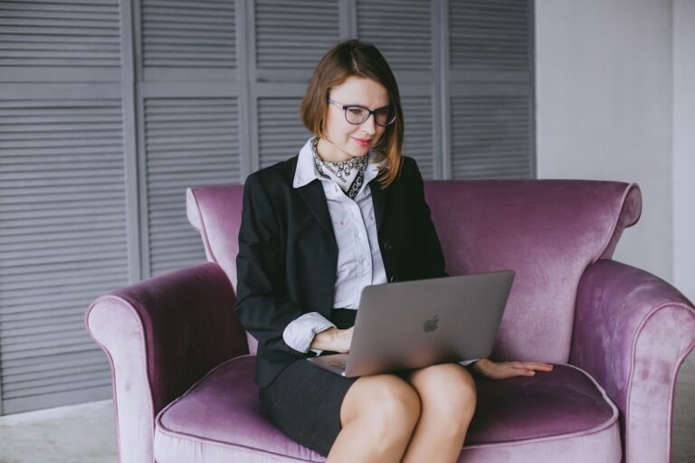 a woman sitting on a couch using a laptop computer