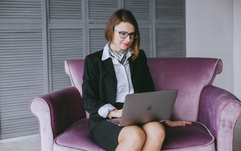 a woman sitting on a couch using a laptop computer