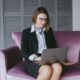 a woman sitting on a couch using a laptop computer