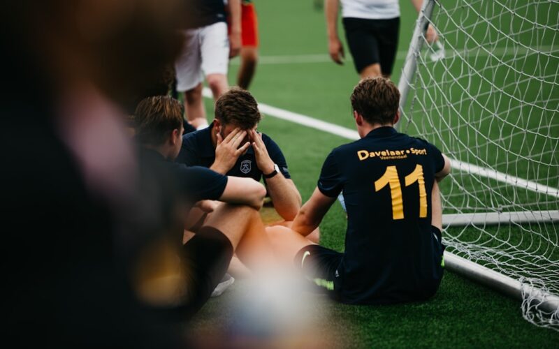 group of men in black and yellow crew neck t-shirts sitting on green grass field