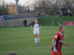 two women are playing soccer on a field