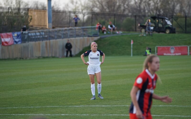 two women are playing soccer on a field