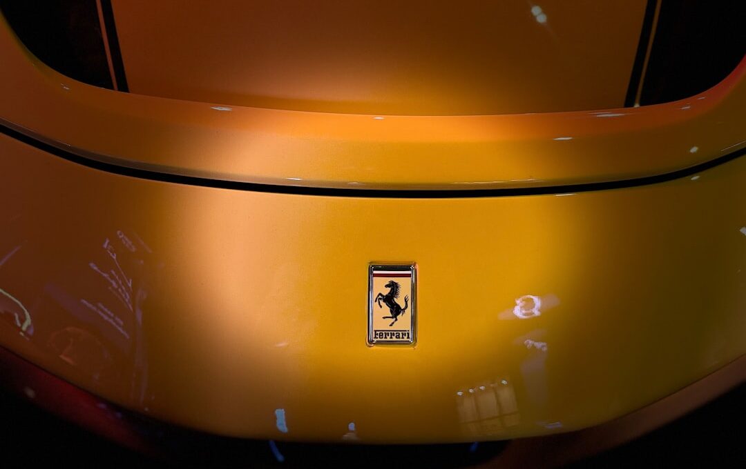 A yellow ferrari car's rear with the iconic emblem