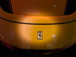 A yellow ferrari car's rear with the iconic emblem