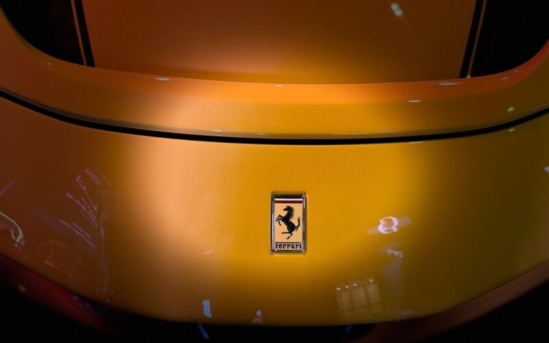 A yellow ferrari car's rear with the iconic emblem