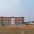 Cricket field with a large brick building and stadium lights