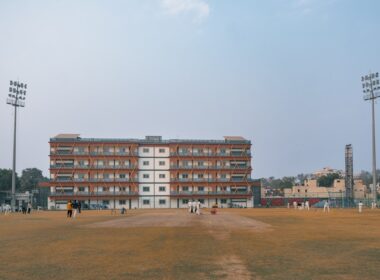 Cricket field with a large brick building and stadium lights