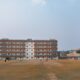 Cricket field with a large brick building and stadium lights