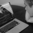 grayscale photo of man looking at macbook pro