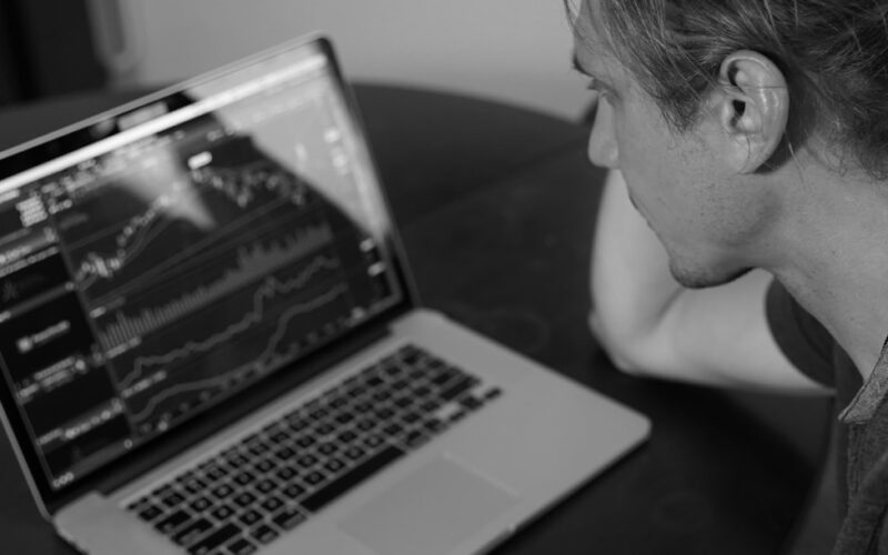 grayscale photo of man looking at macbook pro