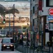 A car driving on a city street past a building with a large dinosaur mural