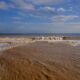 Muddy ocean waves crash onto a sandy beach