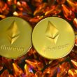 two gold ethereum tokens sitting on top of a pile of crystals