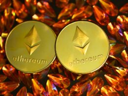 two gold ethereum tokens sitting on top of a pile of crystals