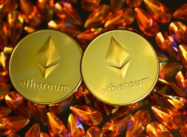 two gold ethereum tokens sitting on top of a pile of crystals