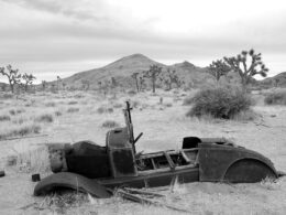 an old car sitting in the middle of a desert