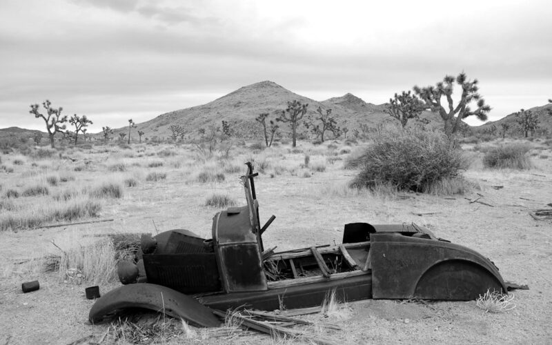 an old car sitting in the middle of a desert