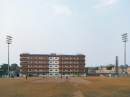 Cricket field with stadium lights and building