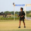 Young man holding a hockey stick on grassy field