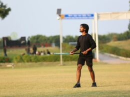 Young man holding a hockey stick on grassy field