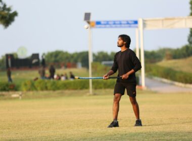 Young man holding a hockey stick on grassy field