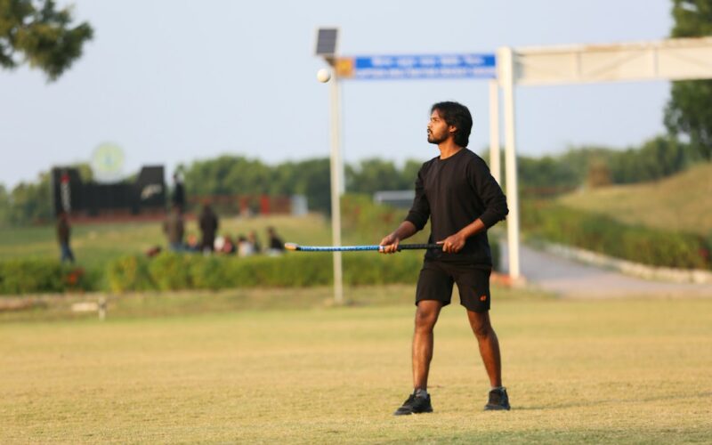 Young man holding a hockey stick on grassy field