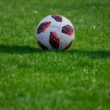white and red soccer ball on green grass field during daytime