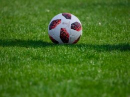 white and red soccer ball on green grass field during daytime