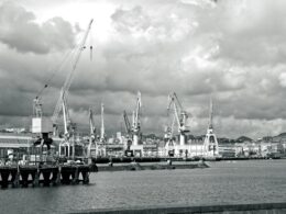 Industrial port with cranes under cloudy sky