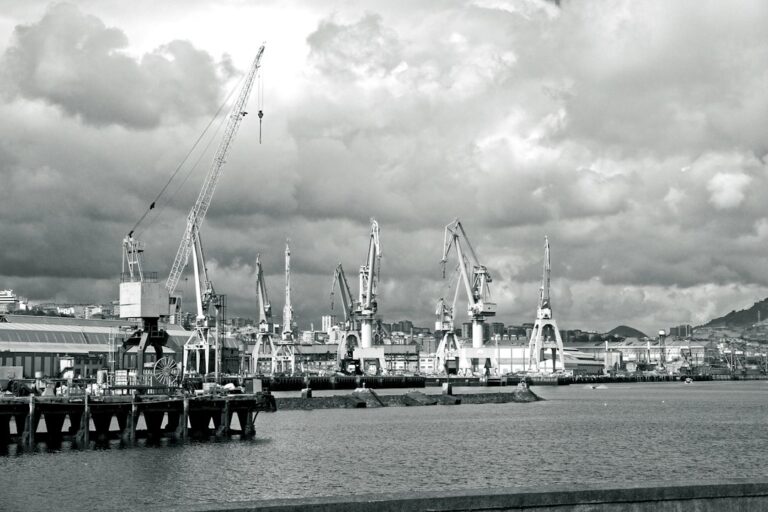 Industrial port with cranes under cloudy sky