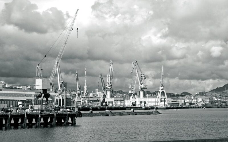 Industrial port with cranes under cloudy sky