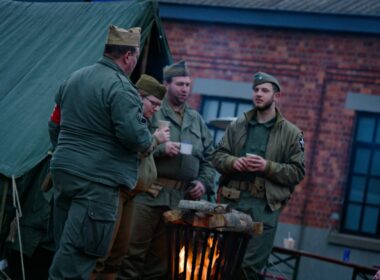Men in vintage military uniforms gathered around a fire