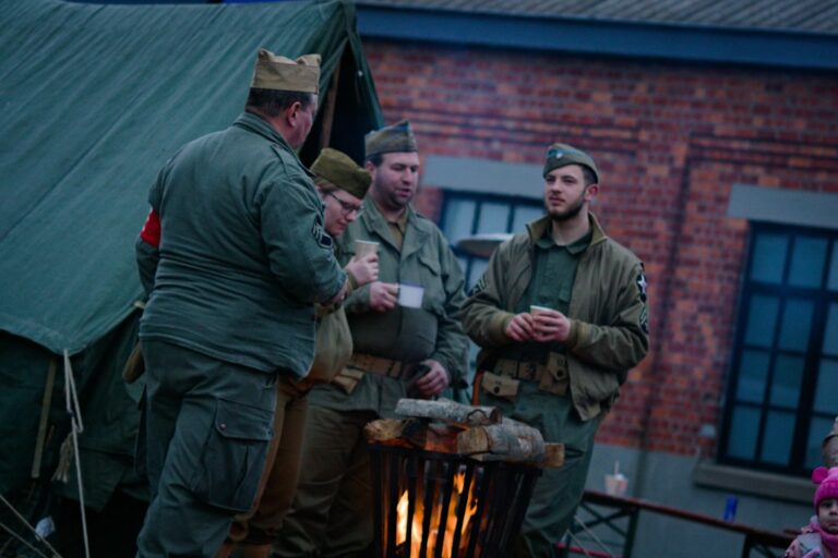 Men in vintage military uniforms gathered around a fire