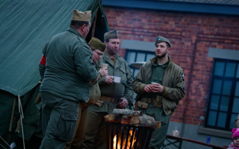 Men in vintage military uniforms gathered around a fire